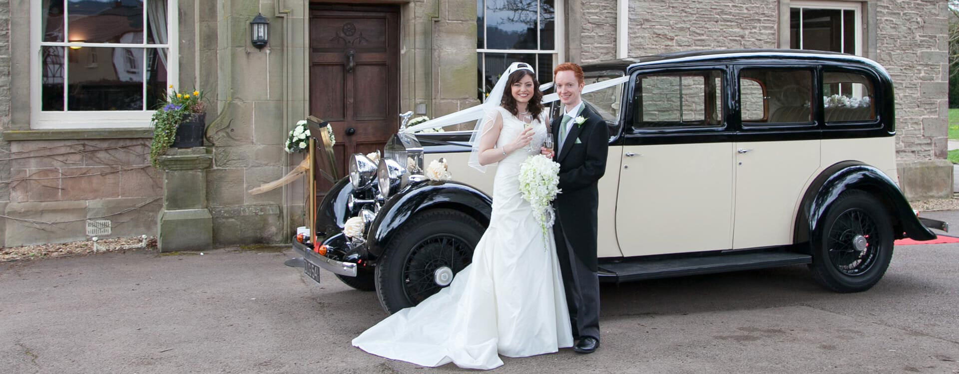 Bride and groom standing by vintage wedding car